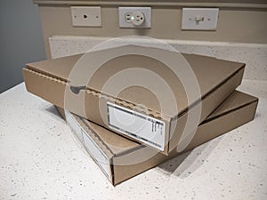 Close up view of two cardboard pizza boxes on a kitchen counter top