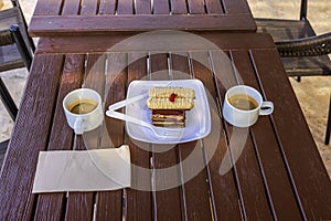 Close-up view of two cups of coffee with pastries on a wooden table in a bar