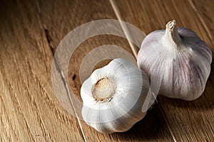 Close up view of two garlic bulbs arranged on a rustic wooden background, shallow depth of field, selective focus, macro