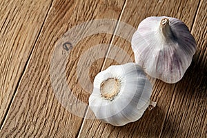 Close up view of two garlic bulbs arranged on a rustic wooden background, shallow depth of field, selective focus, macro