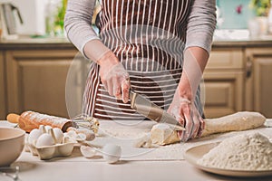 Close-up view of two woman`s hands cut knife dough