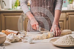 Close-up view of two woman`s hands cut knife dough