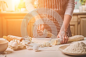 Close-up view of two woman`s hands cut knife dough