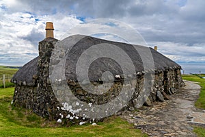 Close-up view of a typical crofter cottage with thick stone walls and a thatched reed roof