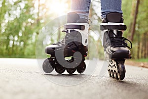 Close up view of unknown person rollerblading in park on sunny day, being on road, spending time in fresh air, enjoying hobby