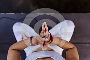 close up view of unrecognizable young asian woman doing yoga in a park. Sitting on the bridge with praying hands position and