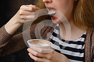 Close up view of unrecognizable young woman eating yogurt