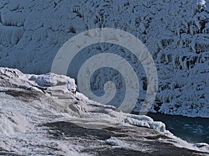 Close-up view of the upper cascade of Gullfoss water fall in southwest Iceland, part of Golden Circle, in winter with rock face.