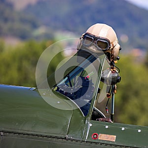 Close-up view of a vintage flight helmet hanging over a navy aircraft