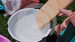 Close up view of Washing clothes on old vintage washboard outdoors. Young Woman washing on old retro washboard