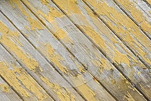 Close-up view of weathered wooden boards with peeling yellow paint