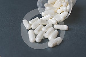 Close up view of white capsules spilling on gray background with space