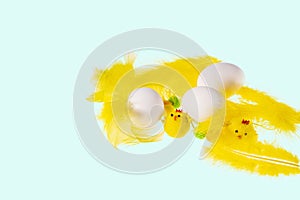 Close up view of white eggs and yellow feathers and chick figures isolated on blue  background. Easter concept