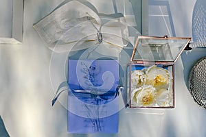 Close up view of white flowers, wedding rings in box with plants inside