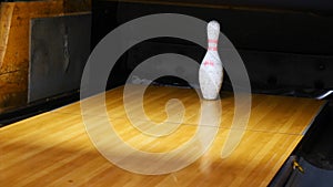 Close-up view of white pins standing in th end of bowling alley lane and rolling bowling ball in a sport club. Media