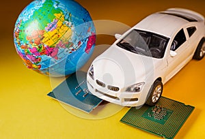 Close up view of a white toy car on top of a microprocessor and a world globe.