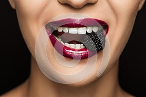 close up view of woman with black jelly candy in mouth