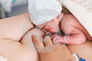 Close-up view of a woman breastfeeding her newborn baby in the hospital room after birth.