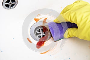 Close up view of woman hand cleaning sink with tomato ketchup.