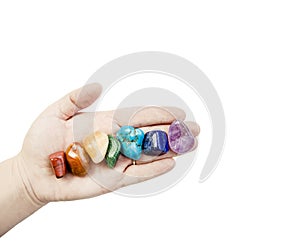 Close up view of woman healer hand showing all seven chakra color crystal stones in color order.