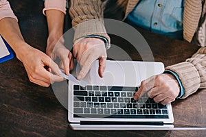 Close-up view of woman helping senior man using laptop and credit card