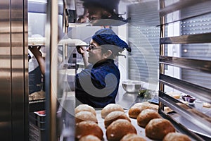 Close up view of woman holding holding rack of rolls in a bakery