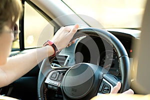 Close up view of woman holding steering wheel driving a car on city street on sunny day