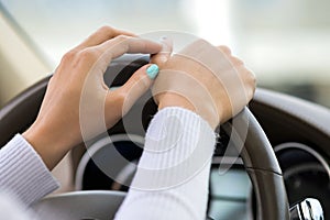 Close up view of woman holding steering wheel driving a car on city street on sunny day