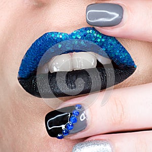 Close up view of woman lips with sparkly blue black lipstick open mouth. Cosmetology fashion makeup beautiful manicure