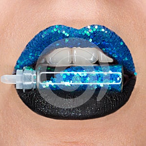 Close up view of woman lips with sparkly blue black lipstick open mouth. Cosmetology fashion makeup, sparkles bottle