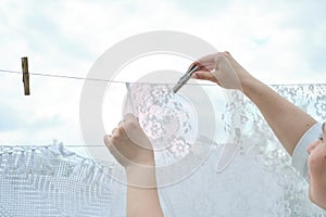 close-up view of a woman pinning her laundry on a line against a backdrop of green trees, emphasizing the practicality