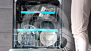 Close up view of woman putting dirty ceramic dish in the dishwasher. Household and helpful technology concept