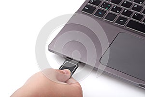 Close-up view of woman`s hand with black SD card. Connects to a reader in a laptop with a keyboard.  on white background