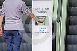 Close-up view of woman sanitizing her hands at sanitation station