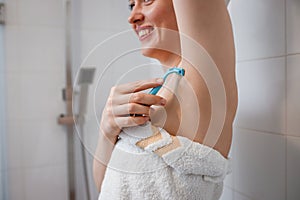 Close-up view of woman shaving her armpits with razor in shower cabin. Depilatory procedure at bathroom