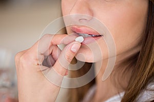 Close up view of woman taking pill to relieve pain