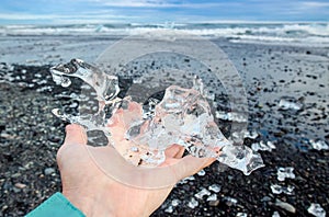 Close up view of woman tourist holding glacier ice on hand.