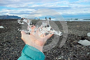 Close up view of woman tourist holding glacier ice on hand.