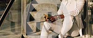 Close-up view of a woman using her mobile phone while sitting on concrete stairs.