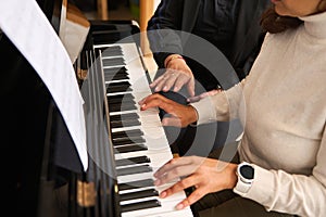 Close-up view of women hands playing piano indoor