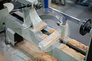 Close up view: wood turning lathe machine with shavings at workshop
