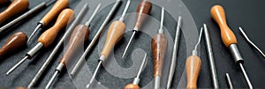 Close-up view of wooden handled awls on dark surface photo
