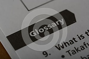 Close up view of the word GLOSSARY. A glossary is a specialized reference or dictionary that provides explanations, definitions,