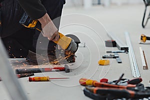 A close-up view of worker cutting metal with angle grinder at construction site