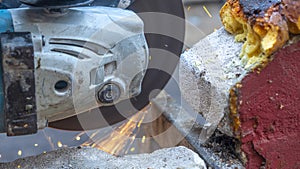 Close-up view of a worker working with angle grinder. Electric wheel grinding on steel structure. Sparks