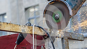 Close-up view of a worker working with angle grinder. Electric wheel grinding on steel structure. Sparks.