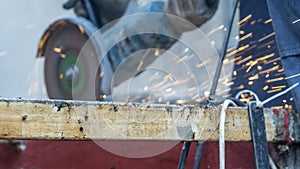 Close-up view of a worker working with angle grinder. Electric wheel grinding on steel structure. Sparks.