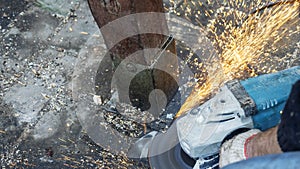 Close-up view of a worker working with angle grinder. Electric wheel grinding on steel structure. Sparks.