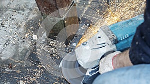 Close-up view of a worker working with angle grinder. Electric wheel grinding on steel structure. Sparks.