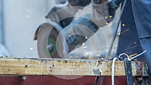 Close-up view of a worker working with angle grinder. Electric wheel grinding on steel structure. Sparks